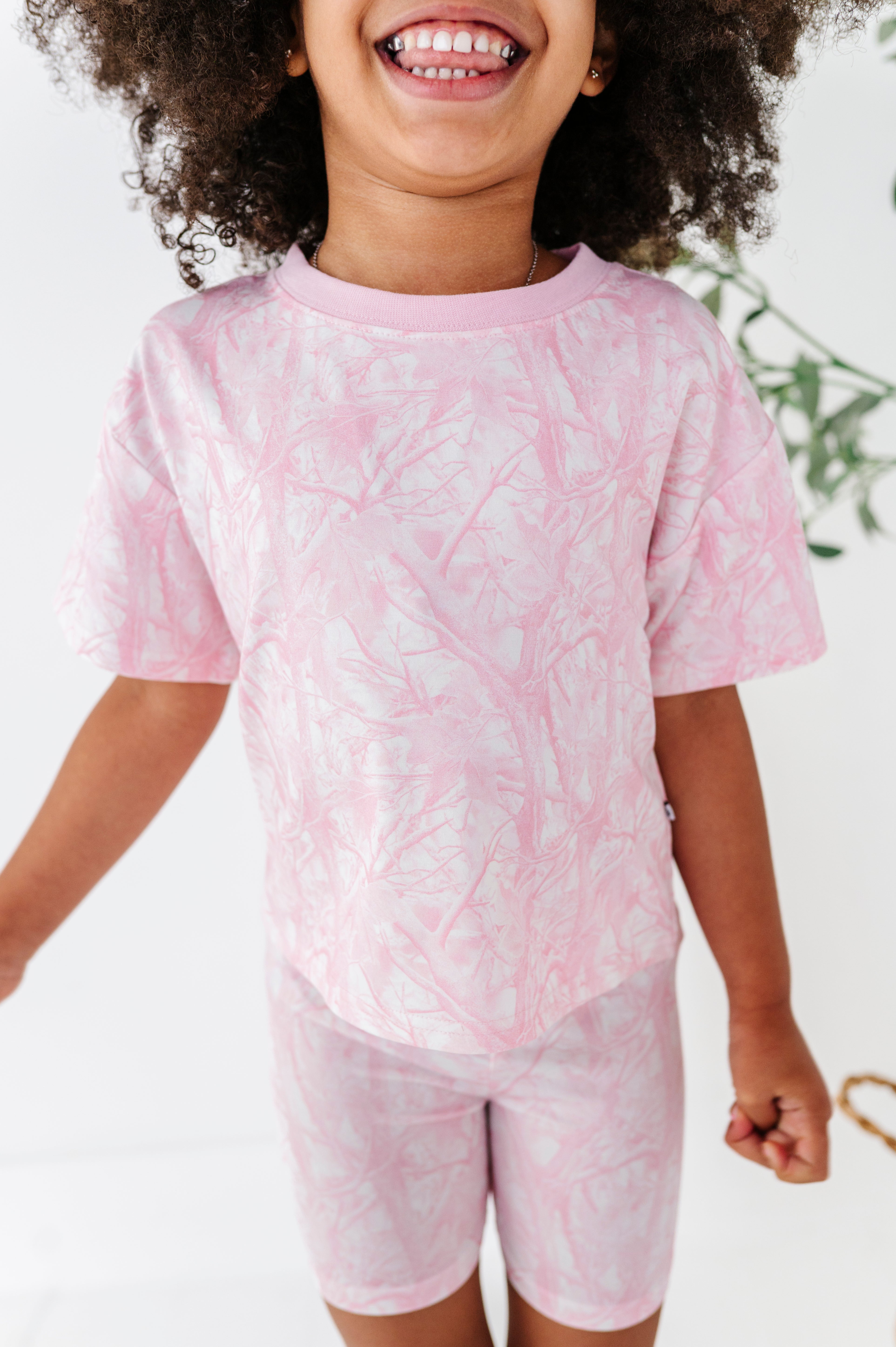 Child wearing a pink tie-dye outfit with a white background
